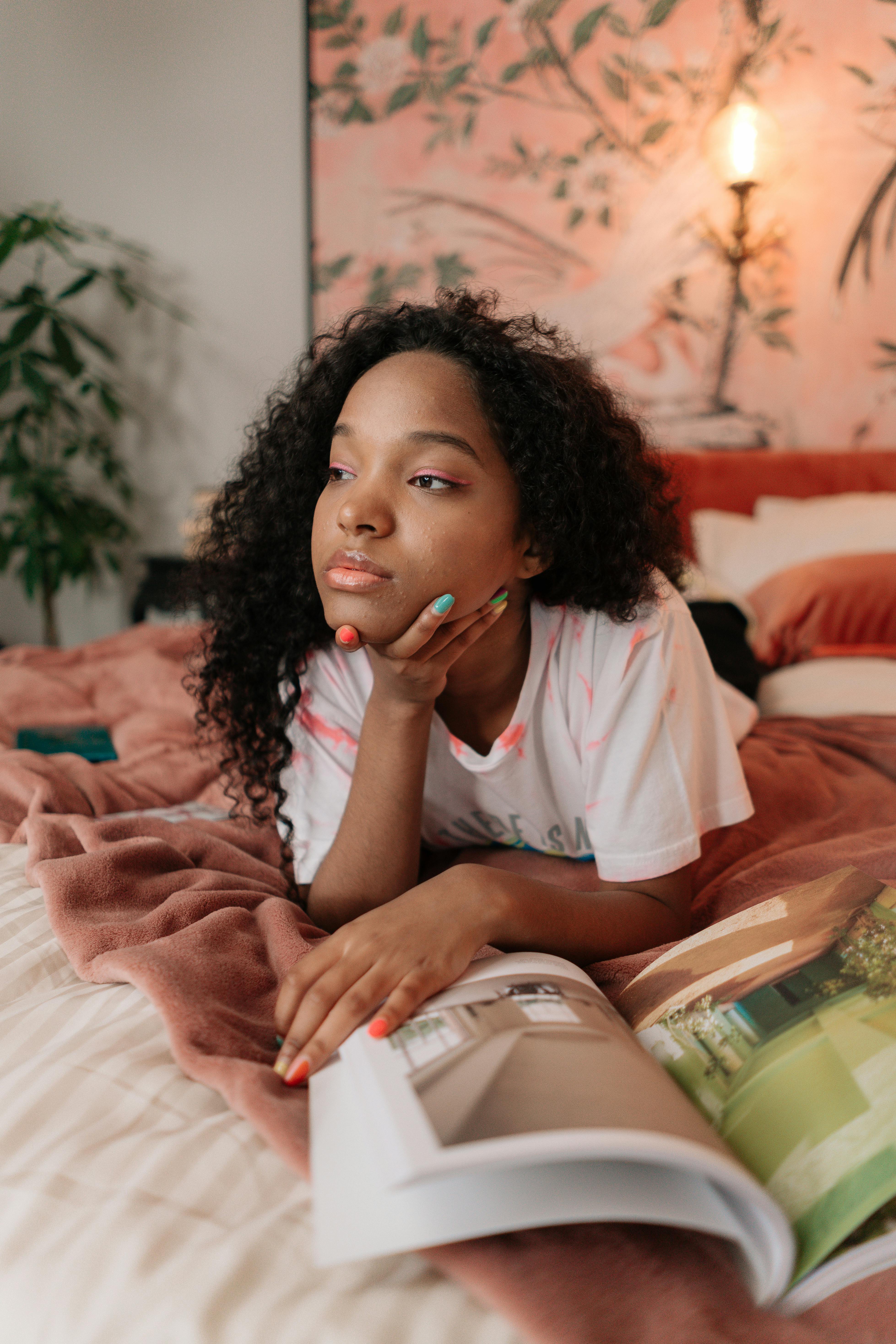 young girl lying on bed with book