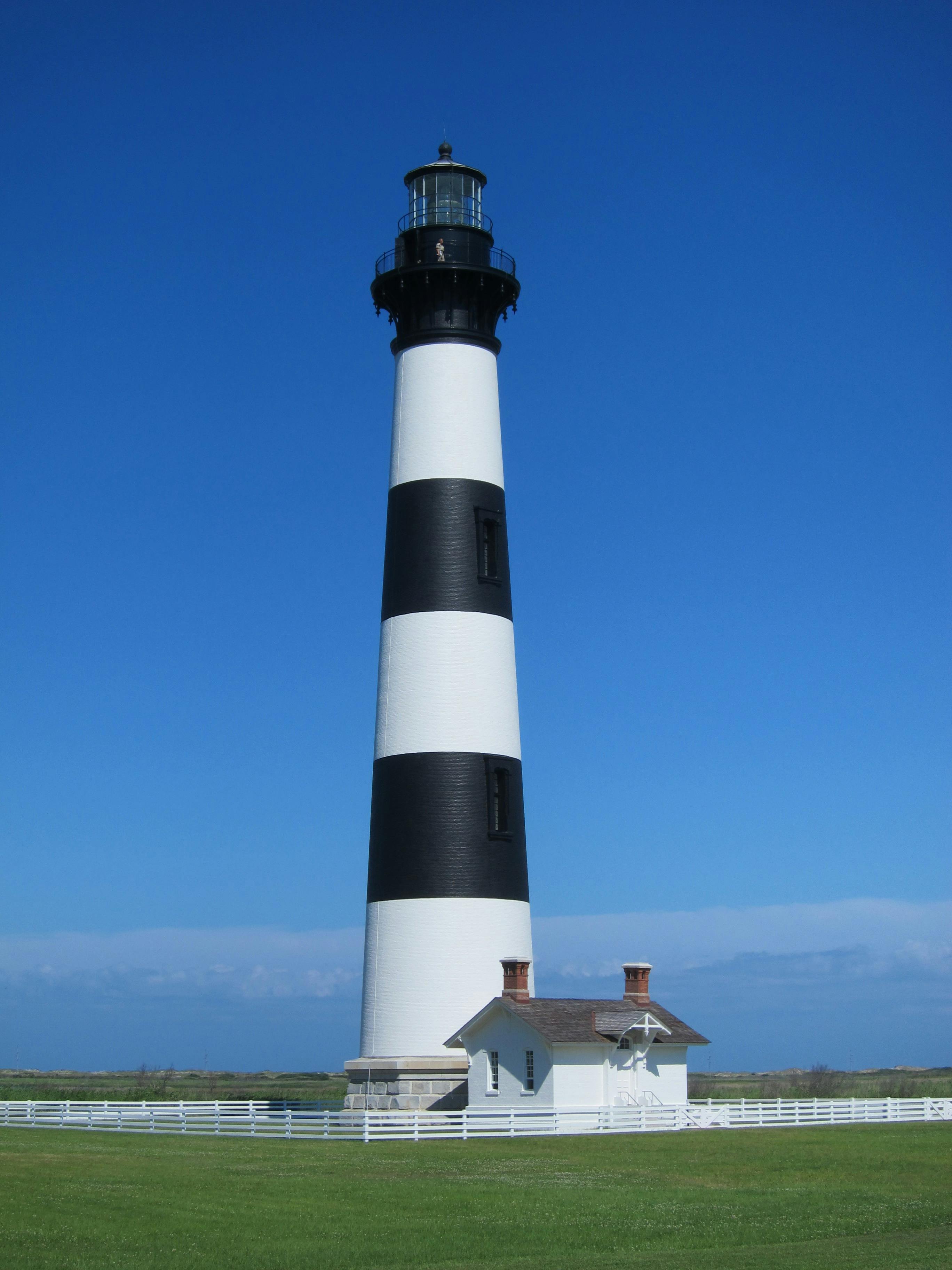 White And Black Striped Lighthouse Beside White House · Free Stock Photo