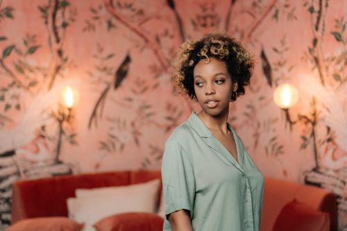 Free Portrait of a fashionable woman indoors with an artistic backdrop, showcasing modern style. Stock Photo