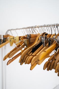 A clean arrangement of wooden clothes hangers on a metal rack in a minimalist bright interior.