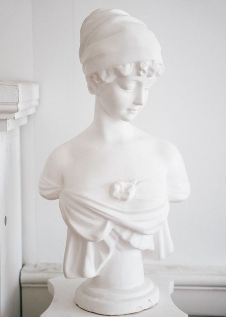 Classic white marble bust of a woman with a serene expression and draped clothing.