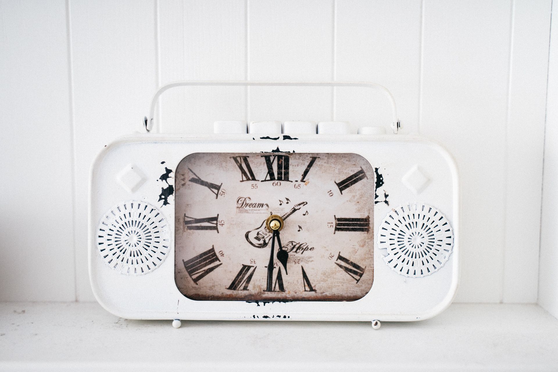 Close-up of a vintage-style analog alarm clock with Roman numerals and speakers, perfect for decor.
