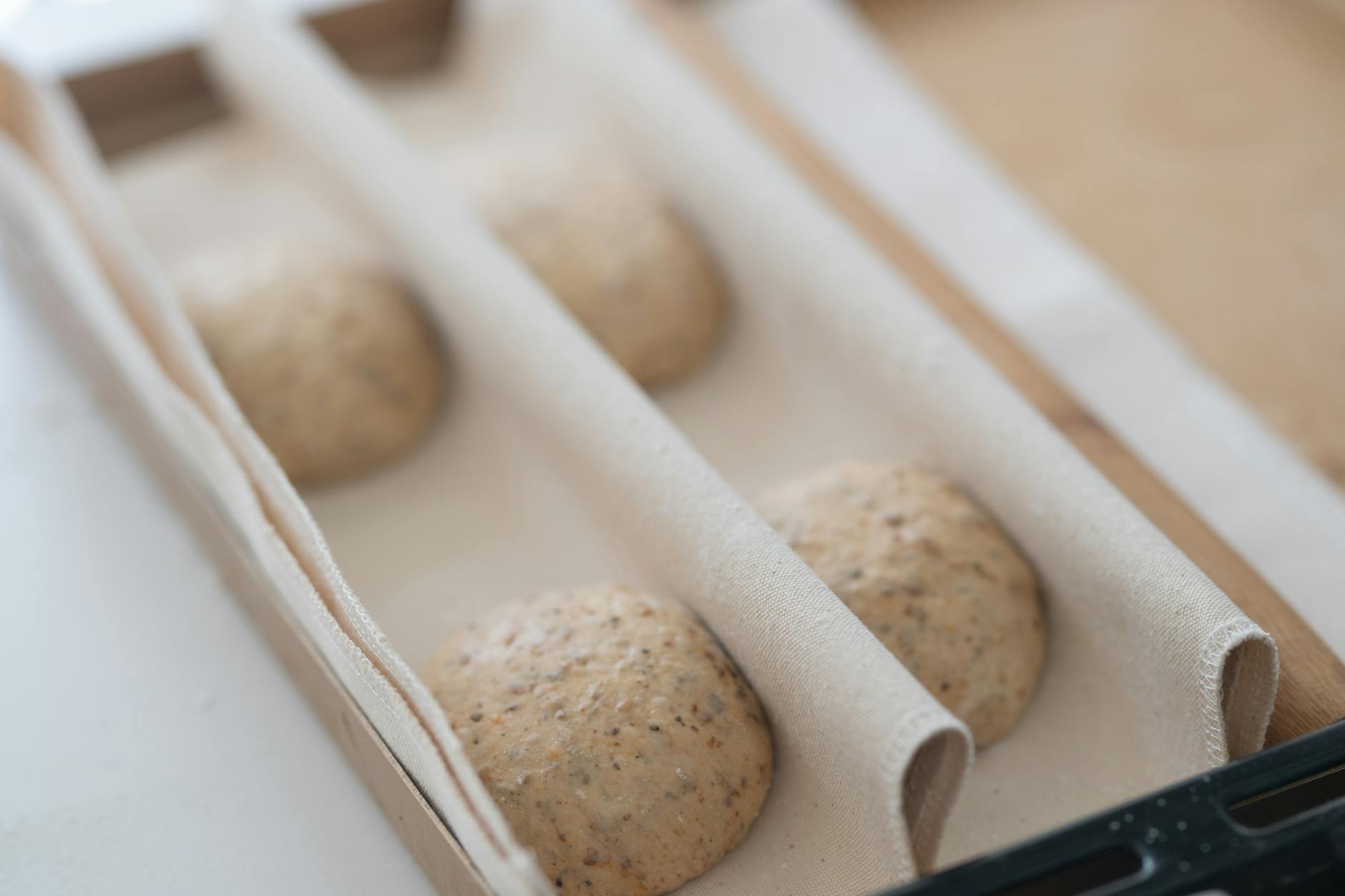 Close-up of artisanal sourdough bread dough proofing in a wooden box, ready for baking.