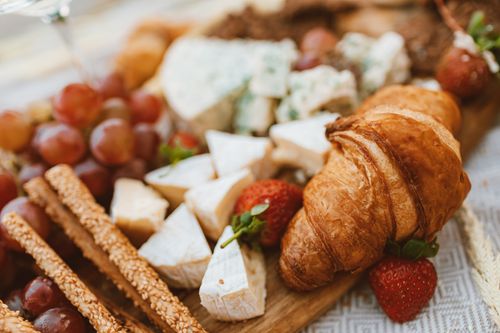 Free Close-up of a rustic breakfast spread featuring cheese, croissant, and fresh fruits. Stock Photo