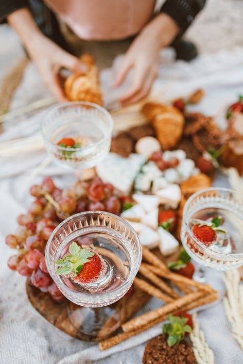 Free A stylish picnic setup featuring strawberries, grapes, and pastries with elegant glassware. Stock Photo