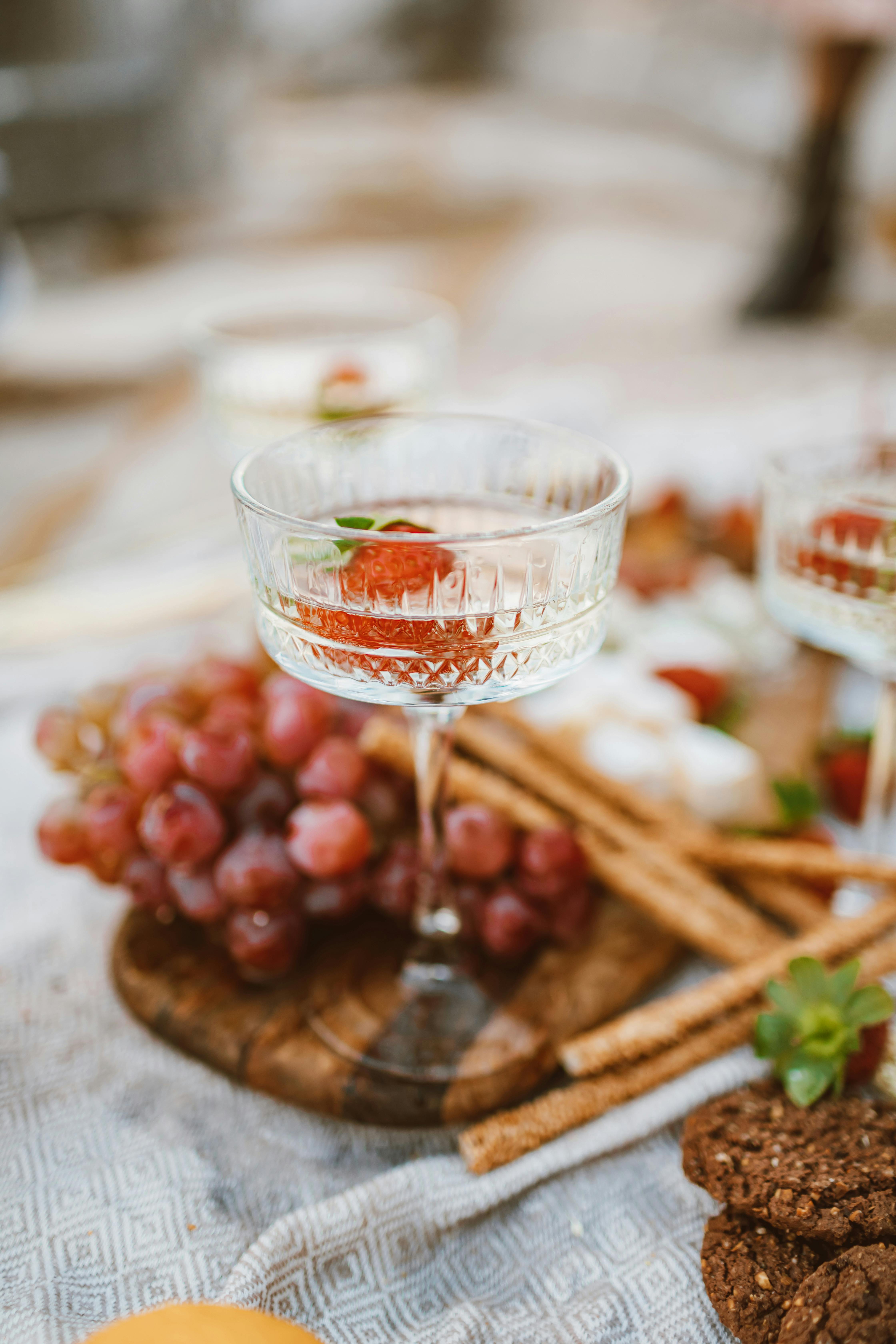 Elegant table setting featuring a wine glass, red grapes, and appetizers for a gourmet dining experience.