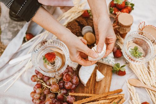 Free A stylish gourmet picnic display featuring cheese, grapes, and sparkling drinks adorned with strawberries. Stock Photo
