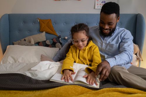Free Father and daughter enjoying a bedtime story together in a cozy indoor setting, fostering family bonding. Stock Photo