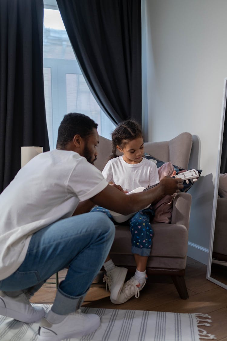 Man In White Shirt Teaching Girl To Play Guitar