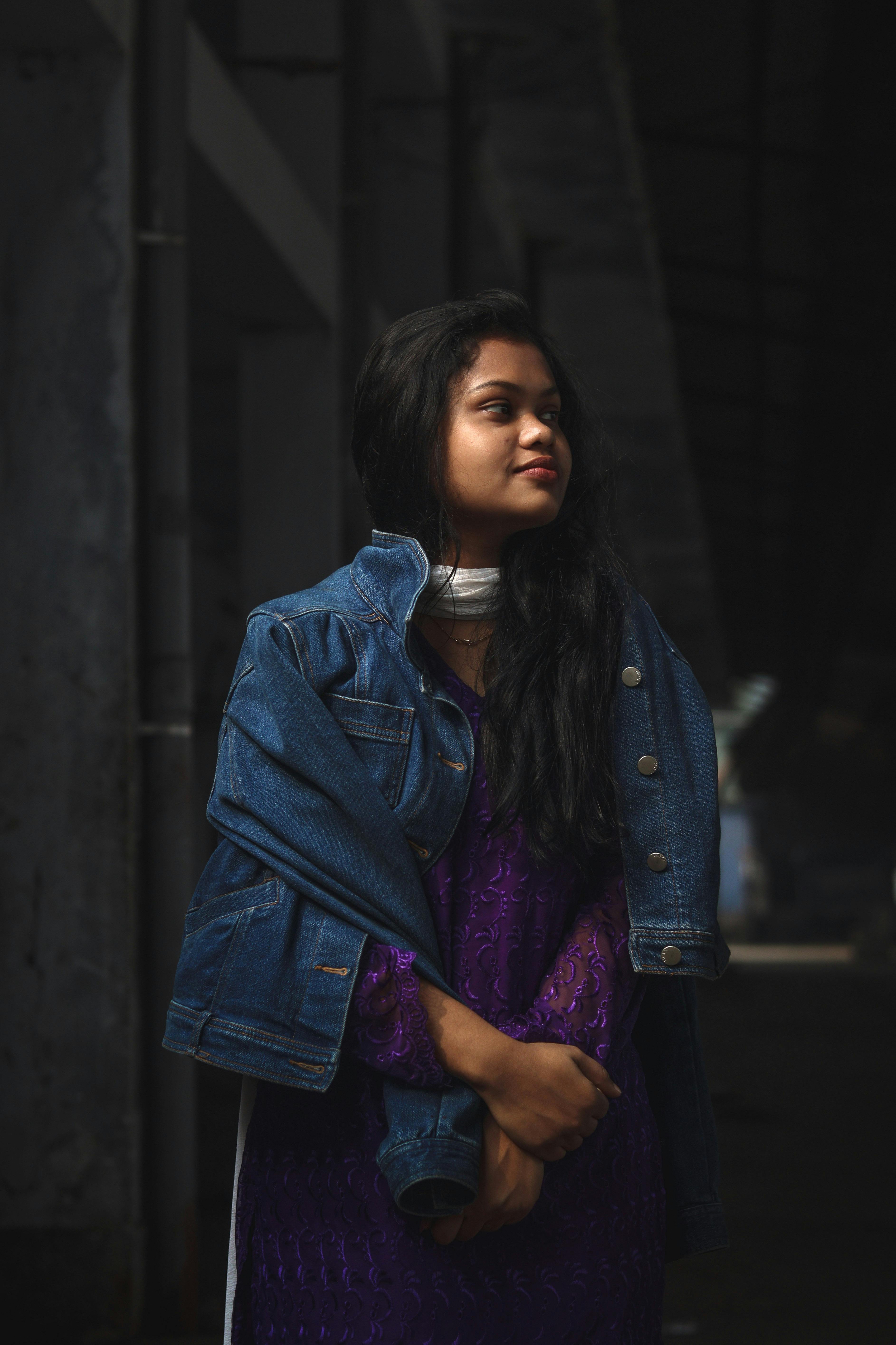 Portrait of a young woman in a denim jacket against an urban backdrop, highlighting modern fashion.