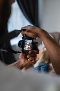 Close-up of hands holding a mirrorless camera capturing a baby's photo indoors.