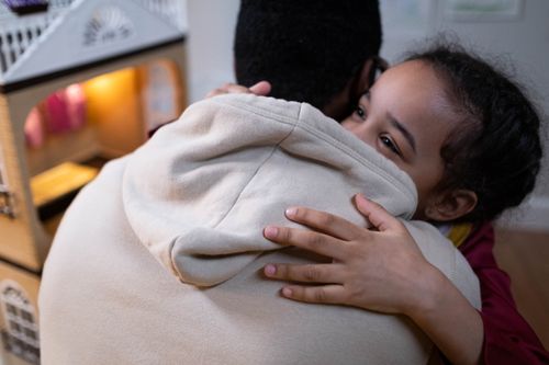 Free Heartwarming moment of a father and daughter sharing a hug inside their home. Stock Photo