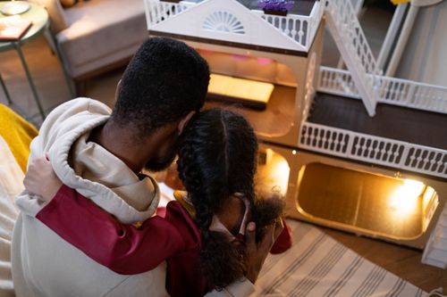 Free Father and daughter share a bonding moment playing with a dollhouse indoors. Stock Photo