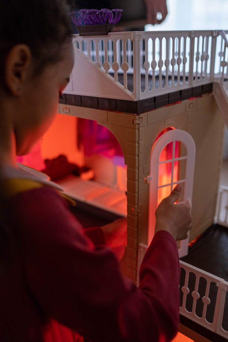 A Girl Playing With A Doll House