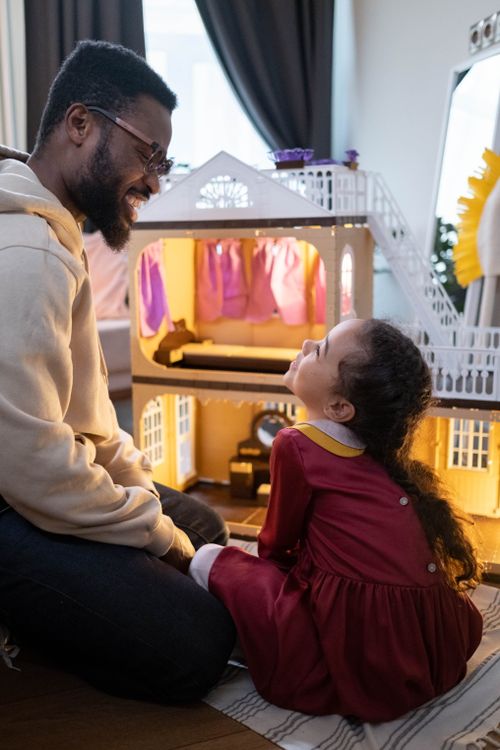 Free A touching moment between a father and daughter enjoying playtime with a dollhouse indoors. Stock Photo
