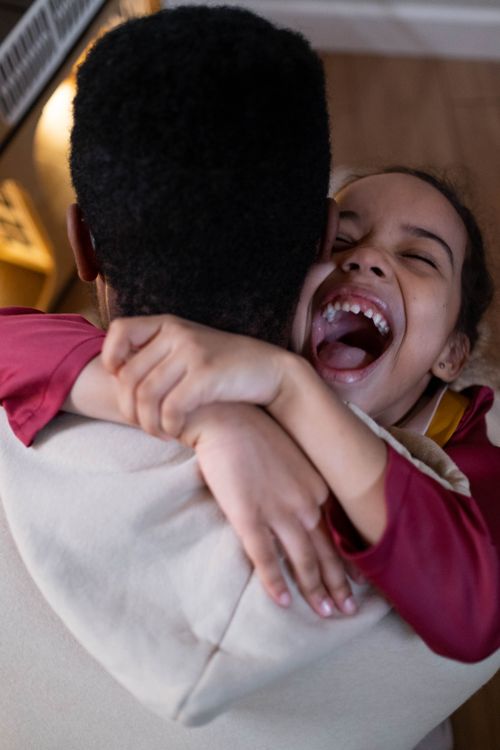 Free A joyful moment of a father hugging his laughing daughter indoors. Stock Photo