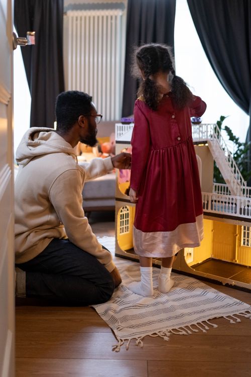 Free A father and daughter enjoy assembling a dollhouse together at home, fostering family bonding. Stock Photo