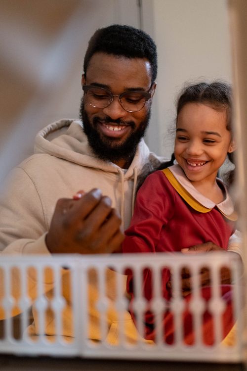 Free A joyful moment of a father and daughter bonding over a toy inside their home. Stock Photo