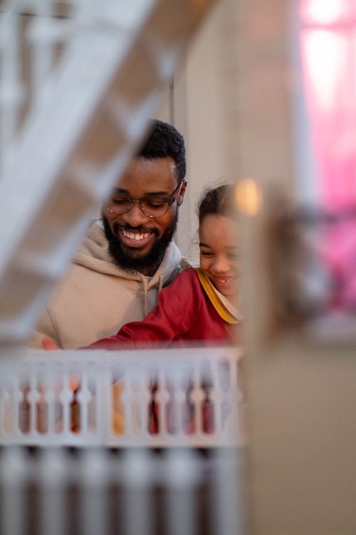 Free A joyful moment between an African American father and daughter playing indoors. Stock Photo