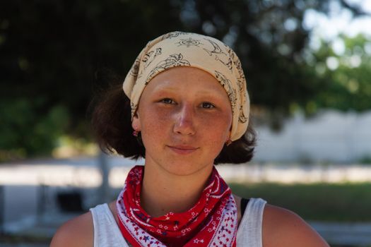 Close-up portrait of a young woman wearing a bandana, captured in natural light outdoors.