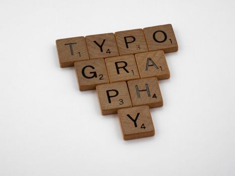 Close-up of wooden Scrabble tiles spelling 'Typography' on a white background.