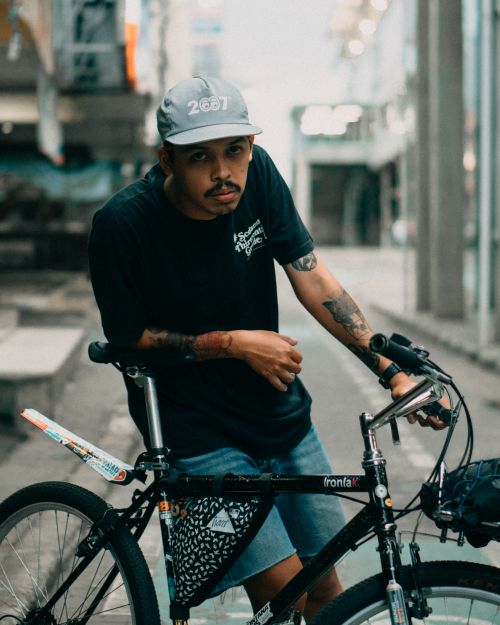 Free Young man with tattoos poses with mountain bike in South Jakarta street scene. Stock Photo