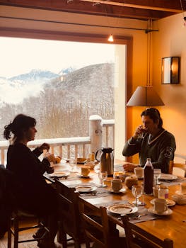 A couple enjoys a warm breakfast with a beautiful snowy mountain backdrop.