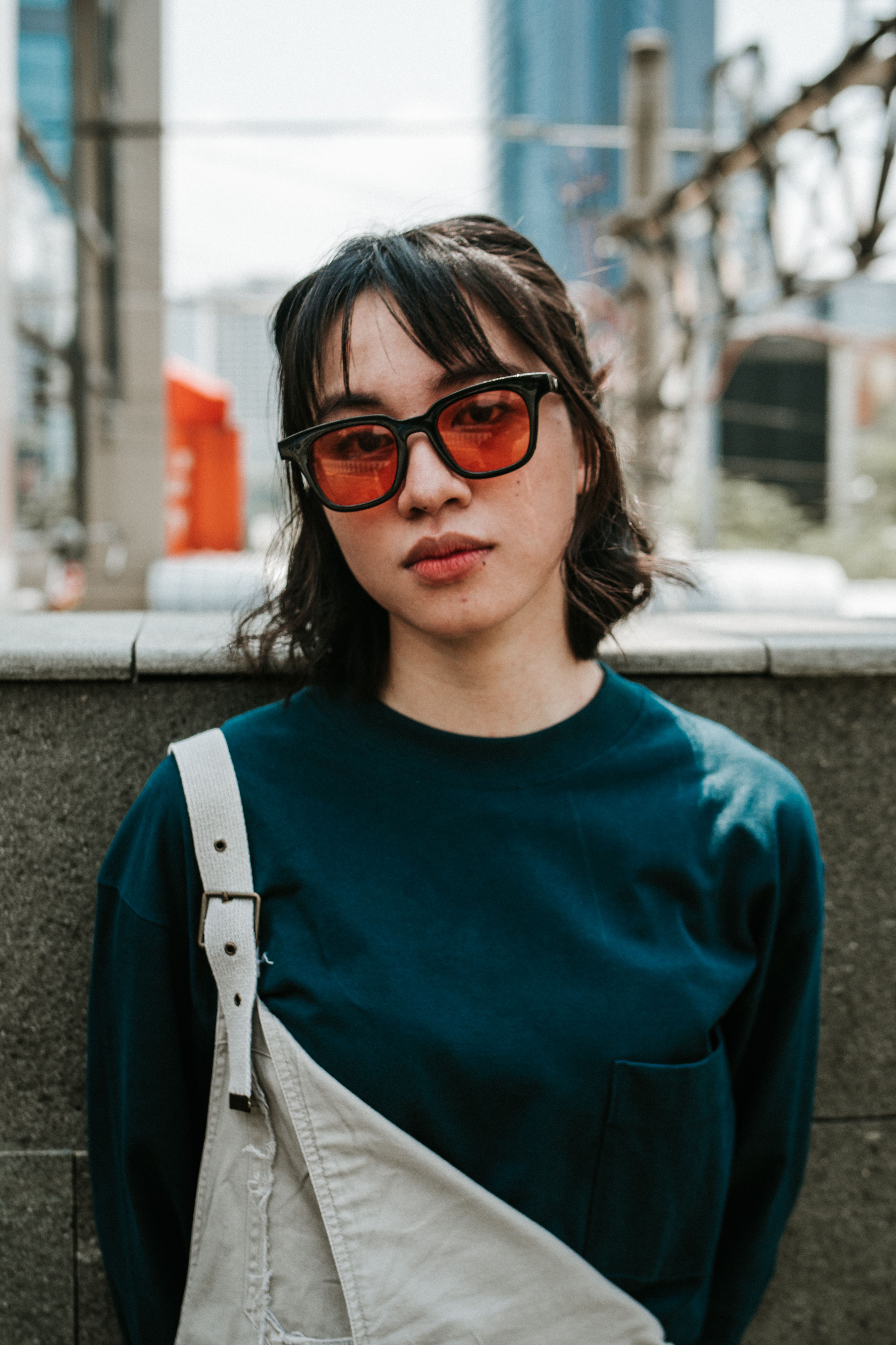 Portrait of a stylish young woman in sunglasses on the streets of Jakarta, showcasing modern street fashion.