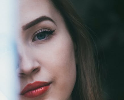 A serene close-up of a woman's face highlighting her red lips and blue eyes.