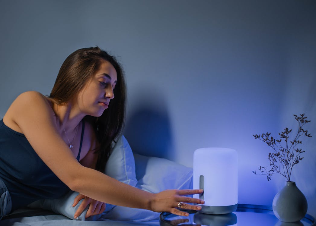 Free A Woman Lying on the Bed Turning on the Lamp Stock Photo