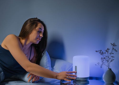 A Woman Lying on the Bed Turning on the Lamp