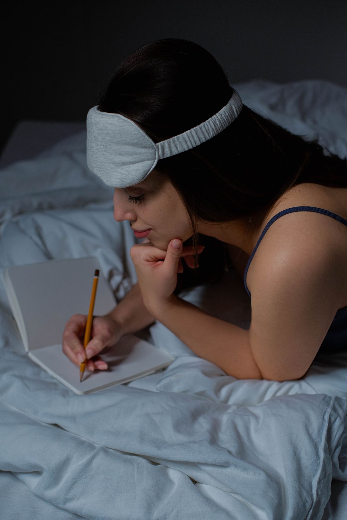 Persona escribiendo sueños en un cuaderno por la noche