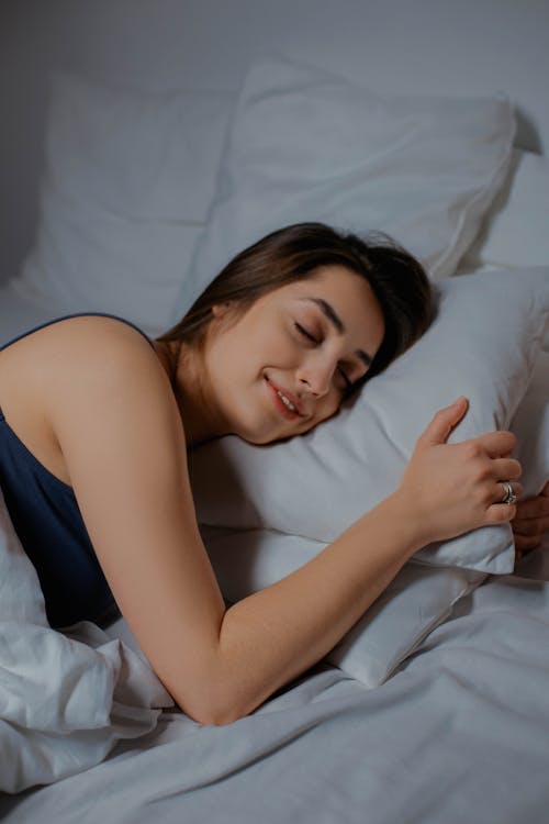 目を閉じてベッドに横たわっている笑顔の女性
