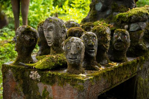 Free Moss-covered stone sculptures with human faces in a verdant Finnish forest setting. Stock Photo