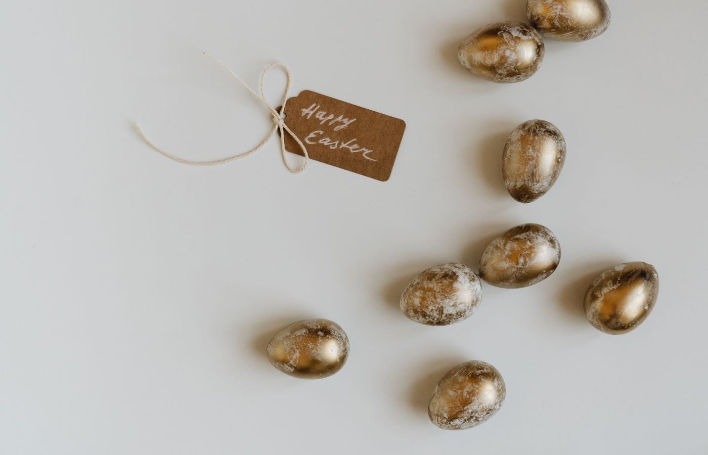 Golden Easter eggs and a 'Happy Easter' tag on a white surface offering copy space.