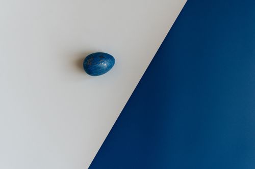 Free A simple blue Easter egg displayed on a contrasting white and blue background, offering ample copy space. Stock Photo