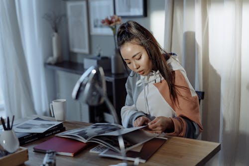 Free A Woman in a Hoodie Jacket Reading a Book Stock Photo