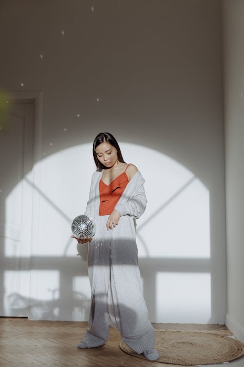 A Woman in Orange Top Holding a Disco Ball