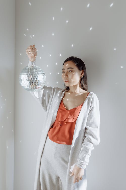 A Woman in Orange Top Holding a Disco Ball