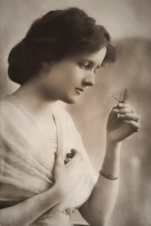 Woman With Sad Face Looking At A Butterfly On Her Hand
