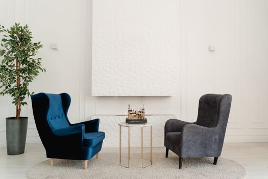 Stylish room setup with blue and grey armchairs, decorative plant, and table.