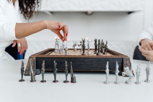Close-up of hands playing chess on a decorative wooden board, showcasing strategic gameplay.