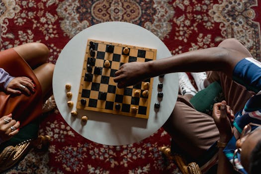 Top view of two people playing chess indoors on a round table.