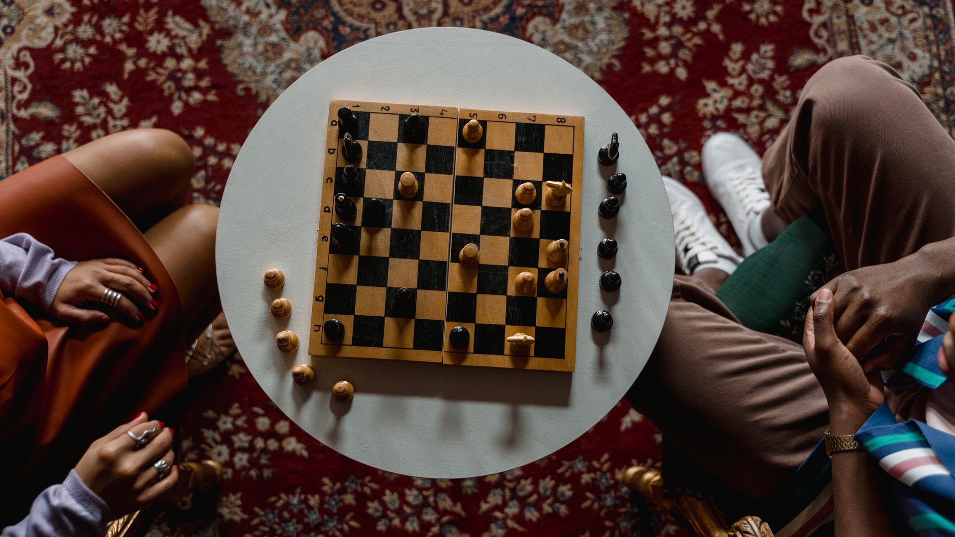 Modafinil for Chess Players: Enhancing Focus and Performance Overhead view of a chess game between two people seated indoors, focused on strategy — modafinil for chess players