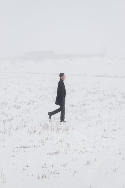 Anonymous man walking on snowy field