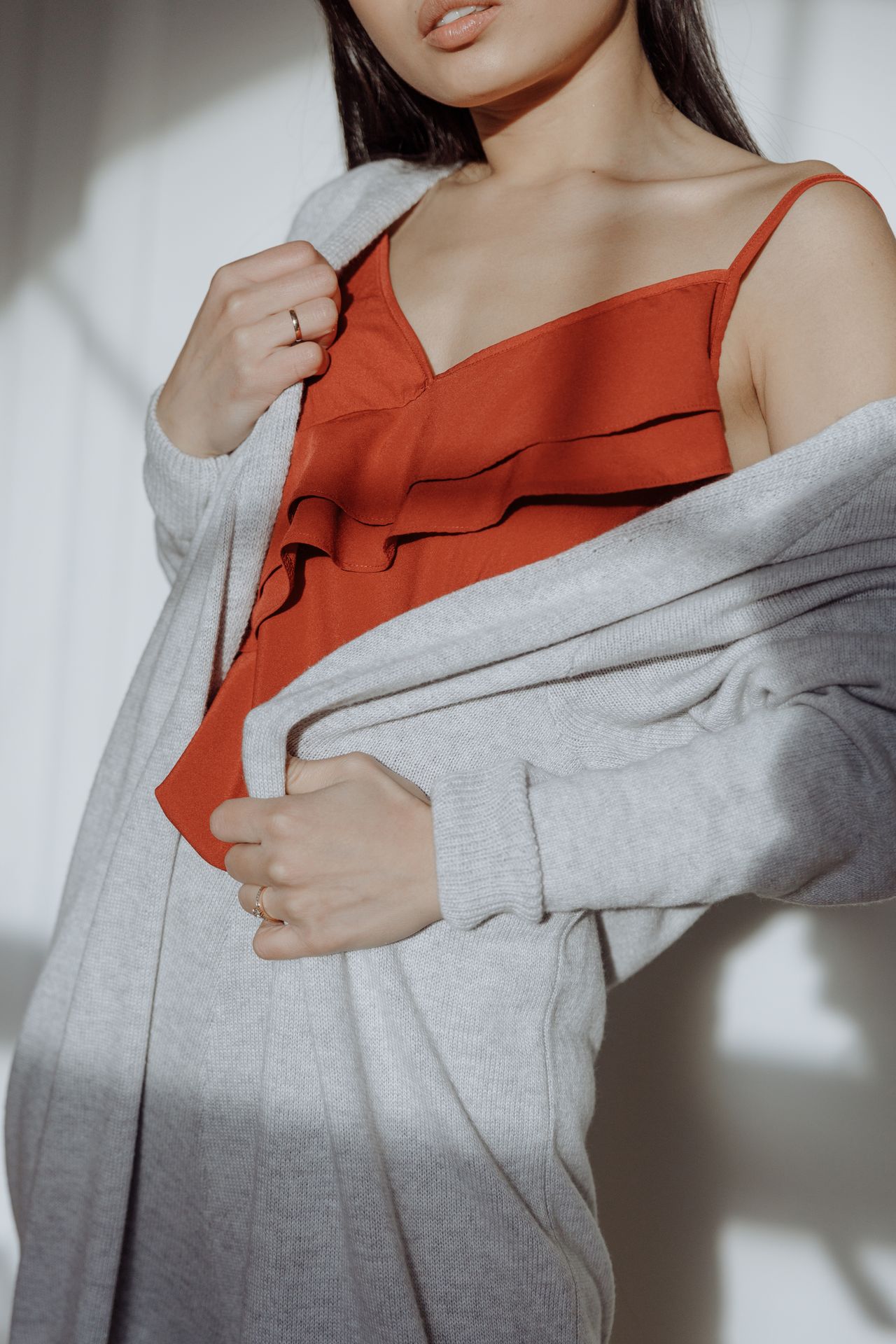 Long gray winter cardigan worn open over a rust-colored camisole
