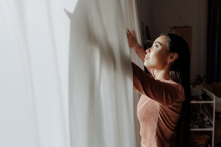 A Woman Opening The Curtain