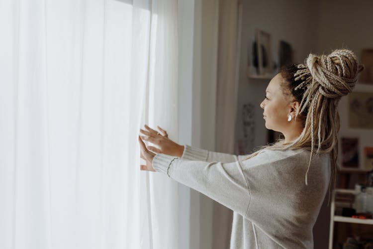 A Braided Hair Woman Opening The Curtains