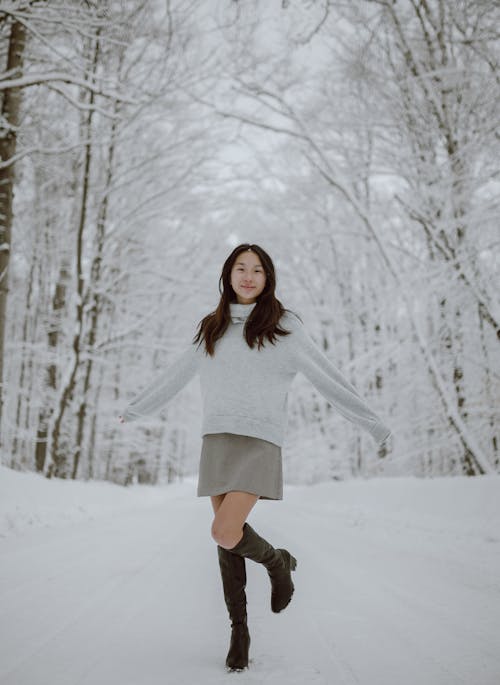 Positive young ethnic lady enjoying winter day in snowy forest