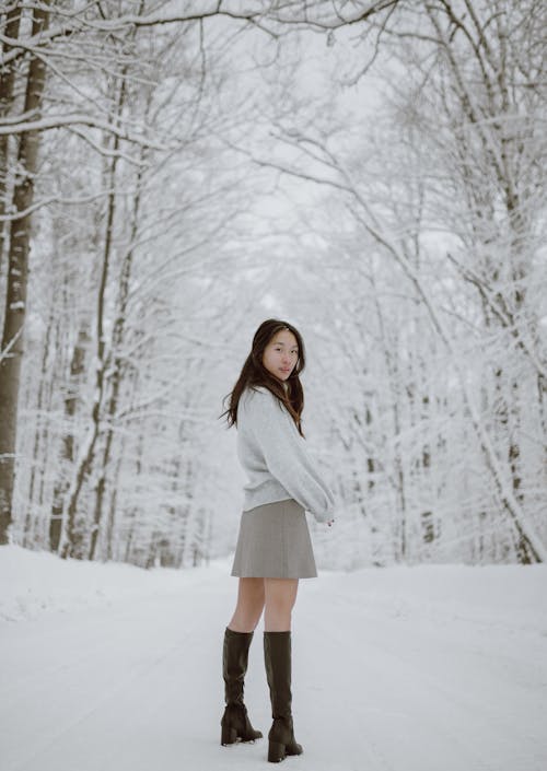 Confident young ethnic woman resting in winter forest covered with snow